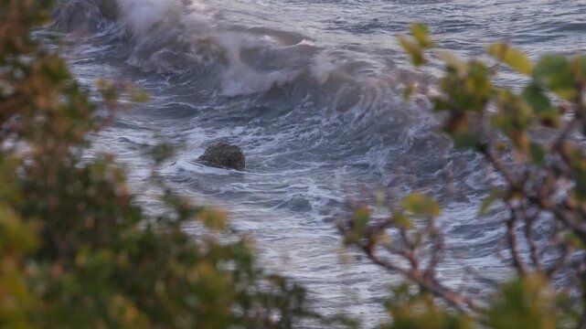 Ocean Waves Rolling Toward a Rocky Coastline. Powerful Sea Waves Breaking Near a Rocky Shoreline. 