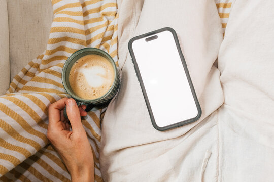 POV drinking coffee and looking at phone at home