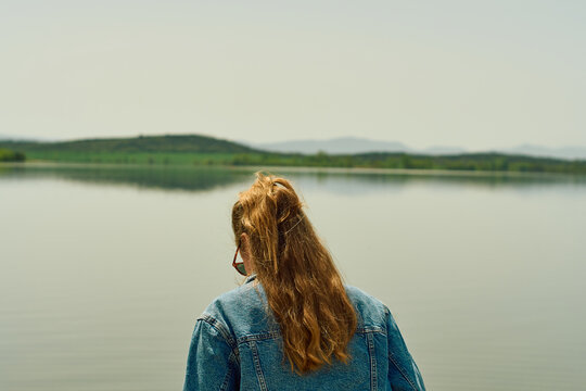 Blonde woman with her back to a lake