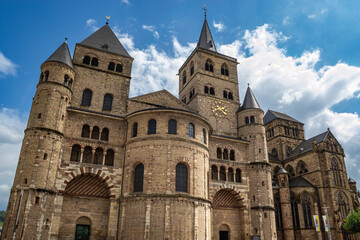 Fototapeta premium Romanesque architecture facade of the historic Trier Cathedral under a blue sky with white clouds
