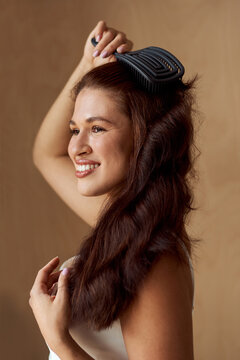 Smiling woman brushes her wavy hair