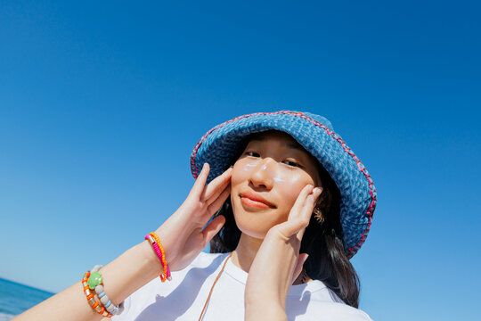 Woman applying sunscreen to face for sun protection