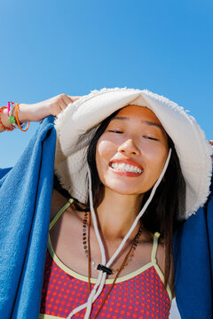 Woman smiling while wearing a bucket hat and swimsuit