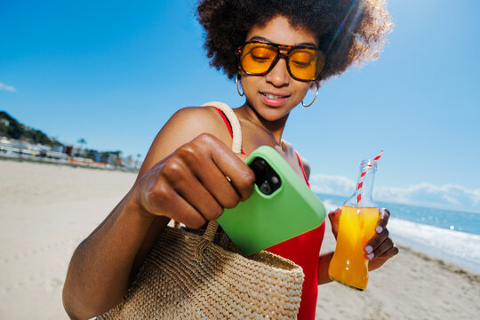Woman enjoying sunny beach vacation holding refreshing drink