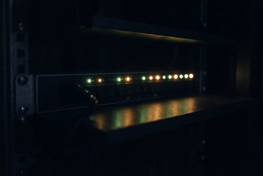 Glowing Status Indicator Lights on Power Distribution Equipment in a Dark Server Room