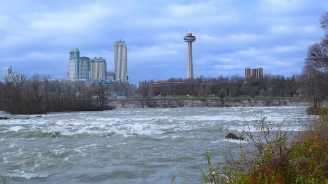 Niagara Falls, USA: This is a scenic view of the Niagara River rapids leading toward the Niagara Falls skyline, featuring the Skylon Tower on the Canadian side.