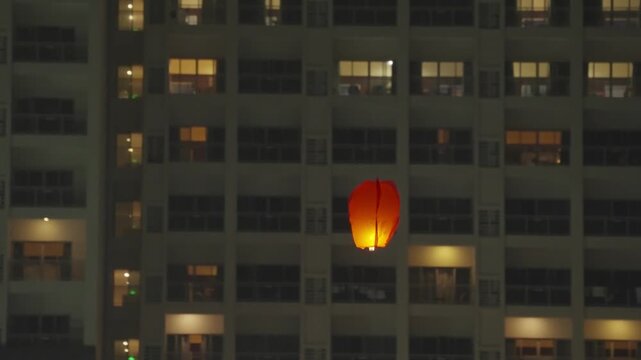 Glowing lantern floating at night in front of apartment building