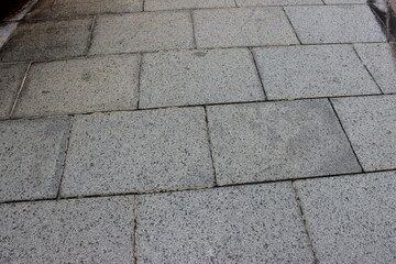 Fototapeta premium Gray granite outdoor walkway surface with consistent speckled stone tile texture.