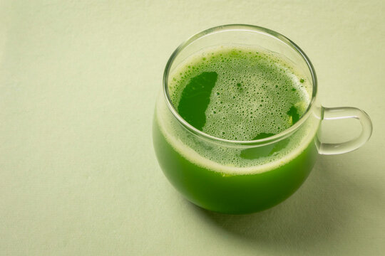 glass cup of fresh home made green cucumber juice on a paper background with copy space, healthy eating concept