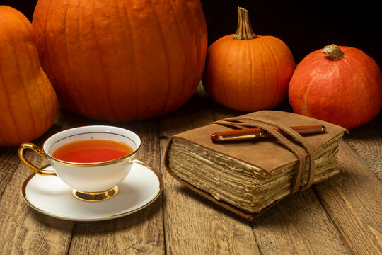 cup of hot tea with retro journal and pumpkis on a rustic wood, Thanksgiving and fall holidays concept