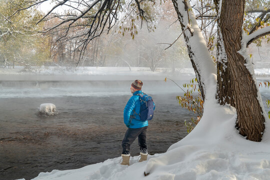 senior male hiker on a shore the Poudre River in Fort Collins, Colorado - foggy fall scenery with a fresh snow