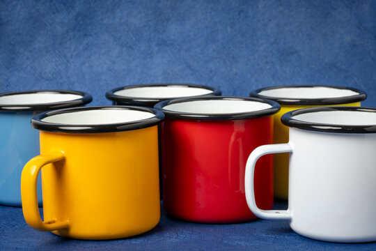 set of enamel metal tea cups of hot tea on paper background