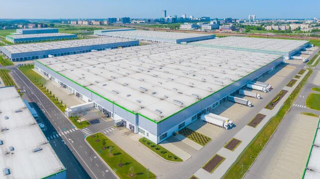Aerial view of massive logistics warehouse with trucks loading and unloading goods efficiently
