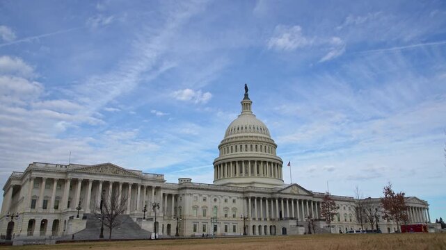 American flag flying over Capitol. American flag with sky clouds over US Capitol. American flag national symbol of Amerika liberty. American flag on historic Capitol dome in Washington DC.