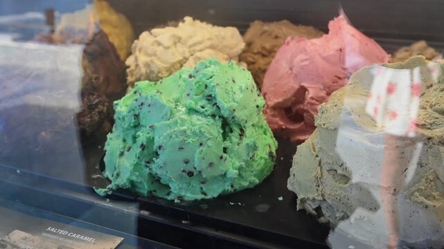 Colorful gelato flavors behind glass in an ice cream shop counter, showing texture and variety for dessert and food concepts.