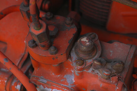 Close Up Weathered Red Tractor Engine Part with Visible Bolts and Nuts Demonstrating Industrial Wear and Vintage Machinery Detail