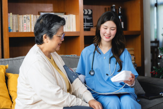Healthcare worker in blue scrubs measures blood pressure. nurse a holds cuff to show test results received. Nurse smile softly appears focused and professional while patient looks calm