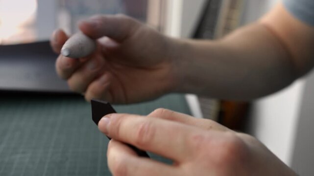 Leather craftsman polishing and burnishing the edge of a leather strap using a slicker tool in a workshop