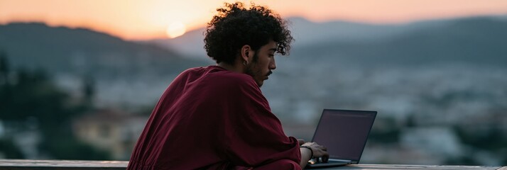 Obraz premium Man working on laptop outdoors at sunset on balcony with city view for remote work banner and productivity background scene