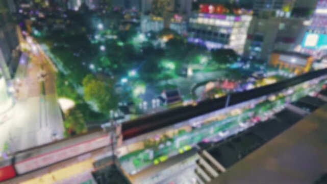Abstract blurred night view of a BTS Skytrain running through the illuminated downtown in Bangkok, Thailand