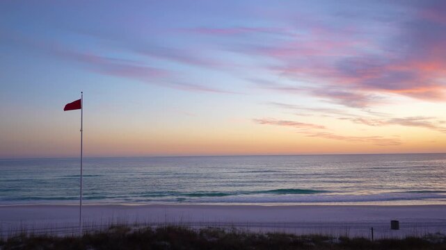Sunset on Florida Beach. Red Warning Flag Waving. Signaling Hazardous Swimming Conditions. USA Panhandle No People. Colorful Sky Wide Shot