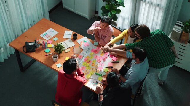 Close up of professional business team hands writing and putting sticky note on scrum task board. Top view of project manager write task and use kanban board to manage time and workflow. Convocation.
