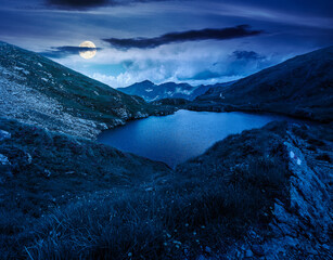 mysterious summer scenery of alpine capra lake with steep slopes at night. fantasy view of transylvania alps, sibiu county. full moon over southern carpathian mountains of romania travel background © Pellinni