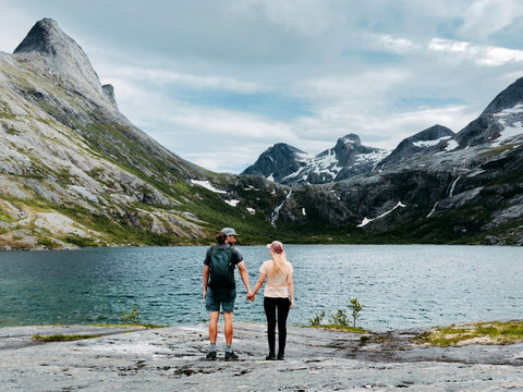 Couple friends travel in Norway people hiking together man and woman holding hands overlooking Aselidalen lake in Bodo, active healthy lifestyle summer vacations romantic tour backpacking trip in wild
