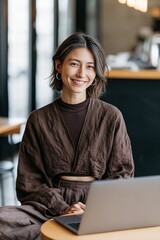 Fototapeta premium Smiling woman working on laptop in cozy cafe wearing brown outfit for business profile banner and social media background