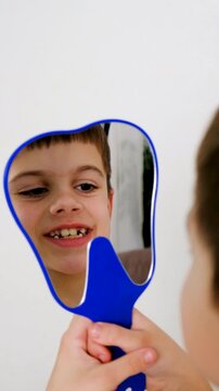 A child at the dentist's office examining his teeth in a mirror. Selective focus.