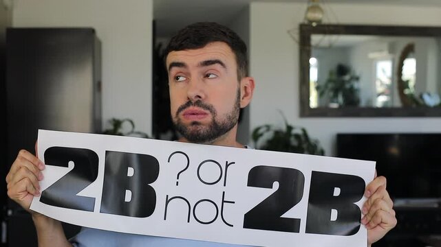 Man holding "TO BE or not TO BE" sign