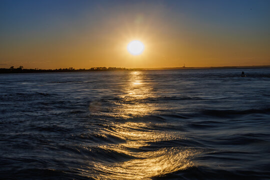 Golden sunset reflecting over rippling, wave-textured water