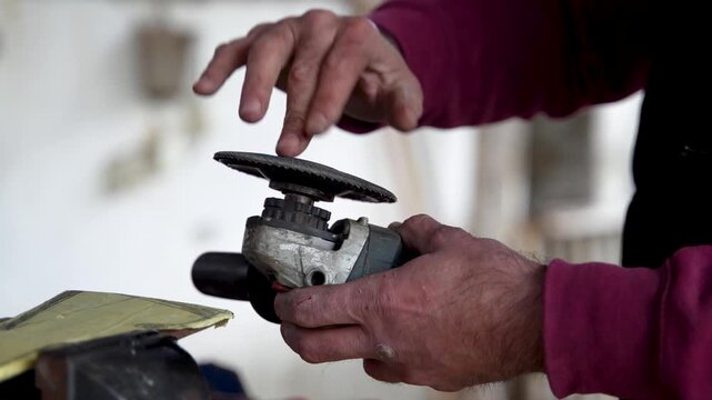 Blacksmith changing grinding disc on angle grinder in workshop