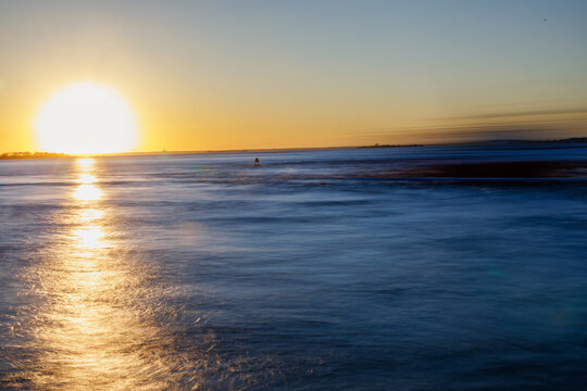 Sunset casting a bold light trail over a calm blue sea