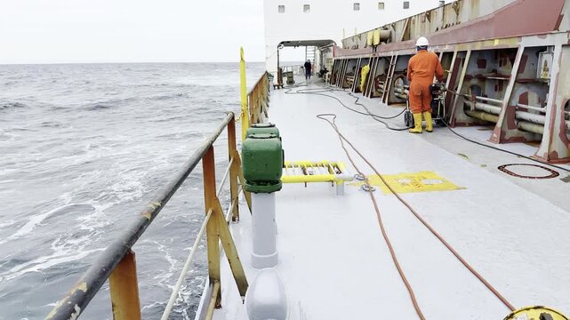 group of marine workers, able seaman, use high pressure machine for maintenance ship. vessel proceeding at ocean. sea waves.