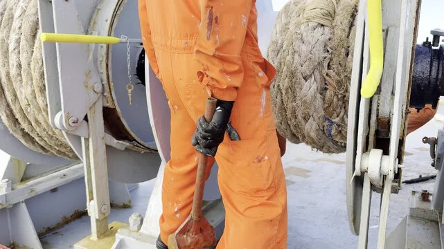 bosun placing mooring rope to the drum of winch, use big hummer. ship mooring equipment. seafarer job 