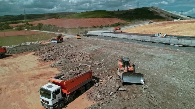 Aerial view of infrastructure construction showing concrete structural work, ground preparation, heavy machinery and site operations across a large rural construction area.