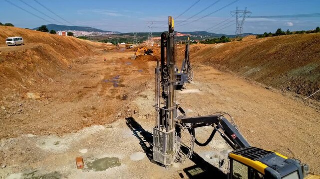 Heavy drilling machinery working at a large infrastructure construction site, preparing the ground with soil stabilization and foundation operations in an excavated road corridor.