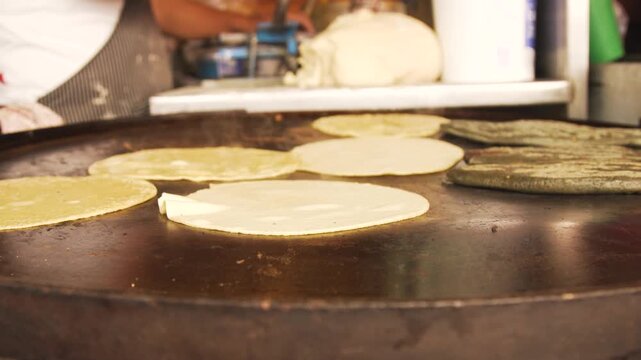 Mexican cook preparing handmade corn tortillas on a comal