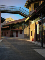 Fototapeta premium Empty paved street with elevated metal walkway connecting renovated buildings in bright daylight