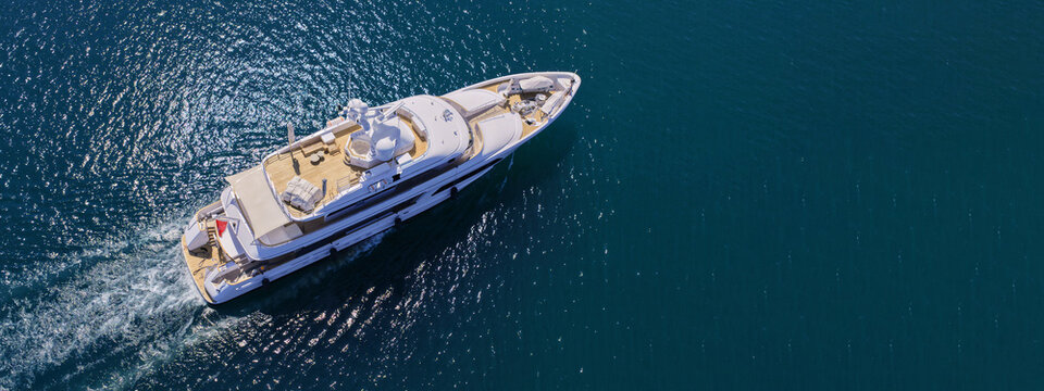 Aerial drone ultra wide panoramic photo with copy space of luxury yacht with wooden deck anchored near port of Port of Fontvieille in deep blue sea, Monaco, France