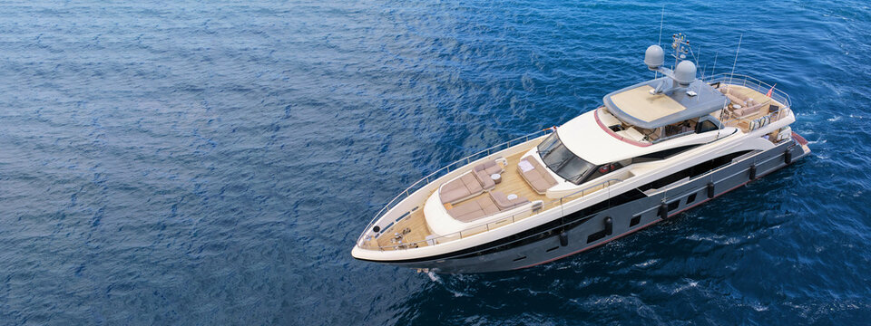 Aerial drone ultra wide panoramic photo with copy space of luxury yacht with wooden deck anchored near port of Port of Fontvieille in deep blue sea, Monaco, France