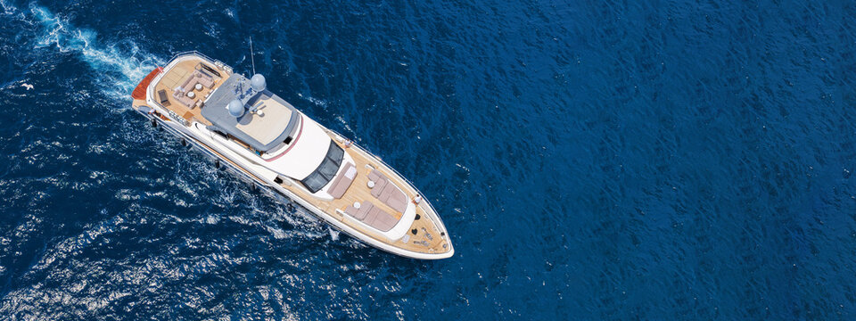 Aerial drone ultra wide panoramic photo with copy space of latest technology modern yacht with wooden deck anchored in deep blue Aegean sea