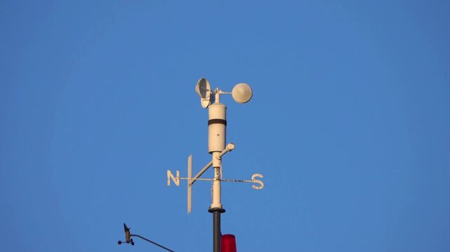 White Anemometer Wind Speed Sensor Spinning Against Clear Blue Sky, Meteorological Weather Station