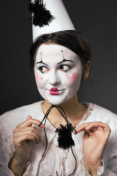 Woman in clown makeup pulling the elastic string of her party hat
