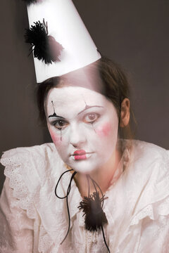 Muted portrait of sad clown woman with light leak looking at camera
