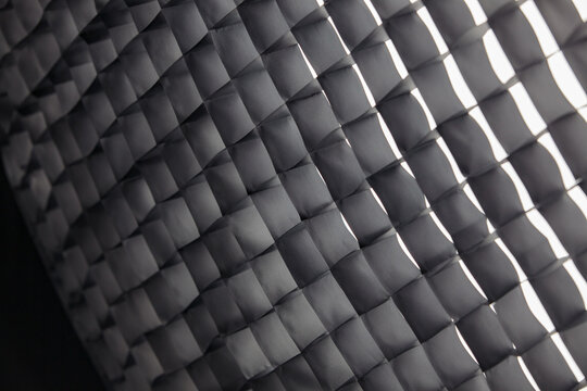 Bright geometric background pattern of a photography softbox honeycomb grid with white light.