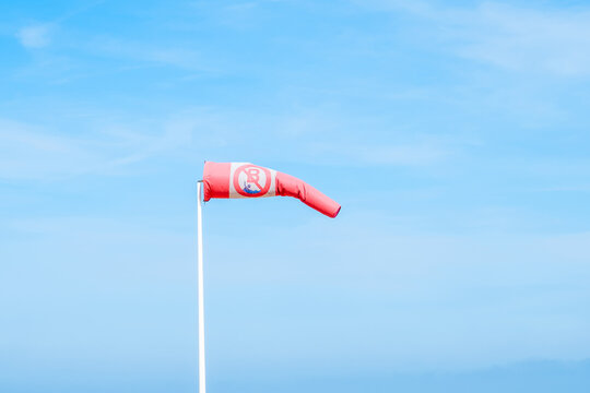 Blue sky, yellow sand on the beach and red white wind indicator - windsock.