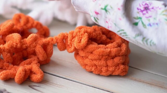 Crop of a teenage girl's hand adjusting a knitting thread on a handmade toy. Children's hobby. Preparing for finger knitting with looped yarn