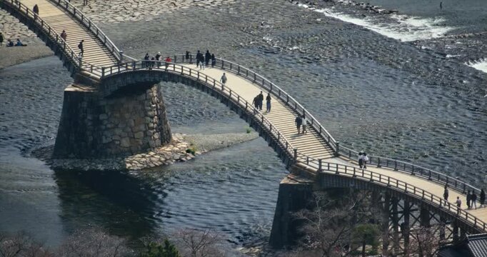 Pedestrians Walking on Historic Wooden Arch Bridge Over River In Japan - High Shot